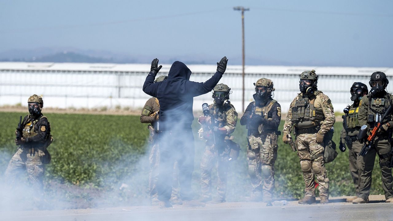 Federal immigration agents toss tear gas at protesters during a raid in the agriculture area of Camarillo, Calif., Thursday, July 10, 2025. (AP Photo/Michael Owen Baker)