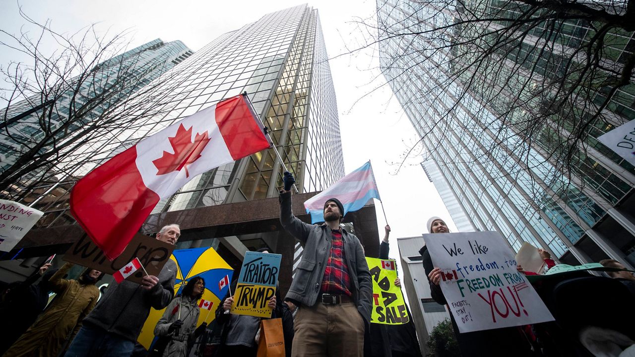 People wave flags and hold signs during a protest outside of the U.S embassy in Vancouver, British Columbia, Tuesday, March 4, 2025. (Ethan Cairns/The Canadian Press via AP, file)