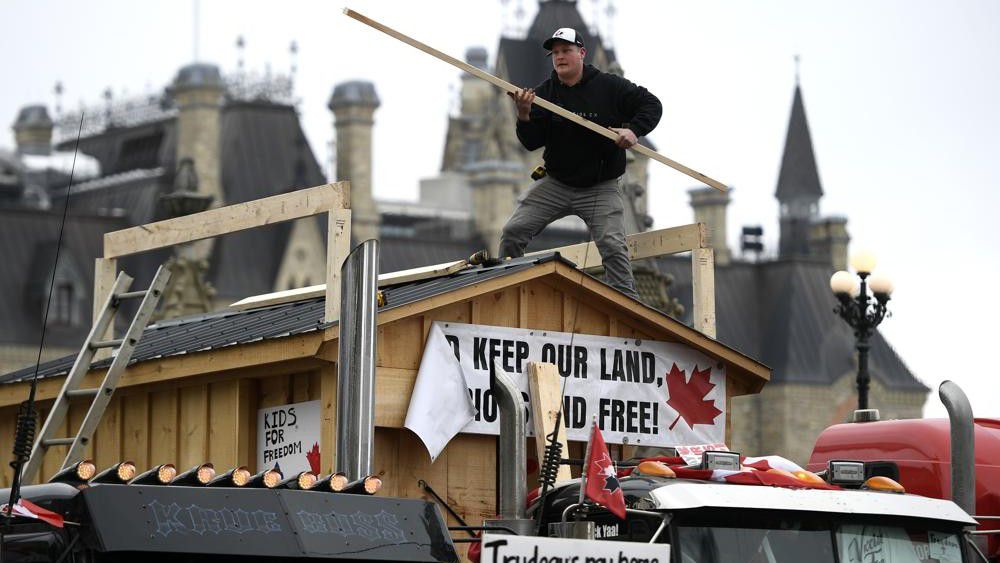 A protester builds a platform on top of a shed attached to a flatbed truck on Wellington Street as a protest against COVID-19 restrictions continues in Ottawa, on Thursday, Feb. 10, 2022. (Justin Tang /The Canadian Press via AP)