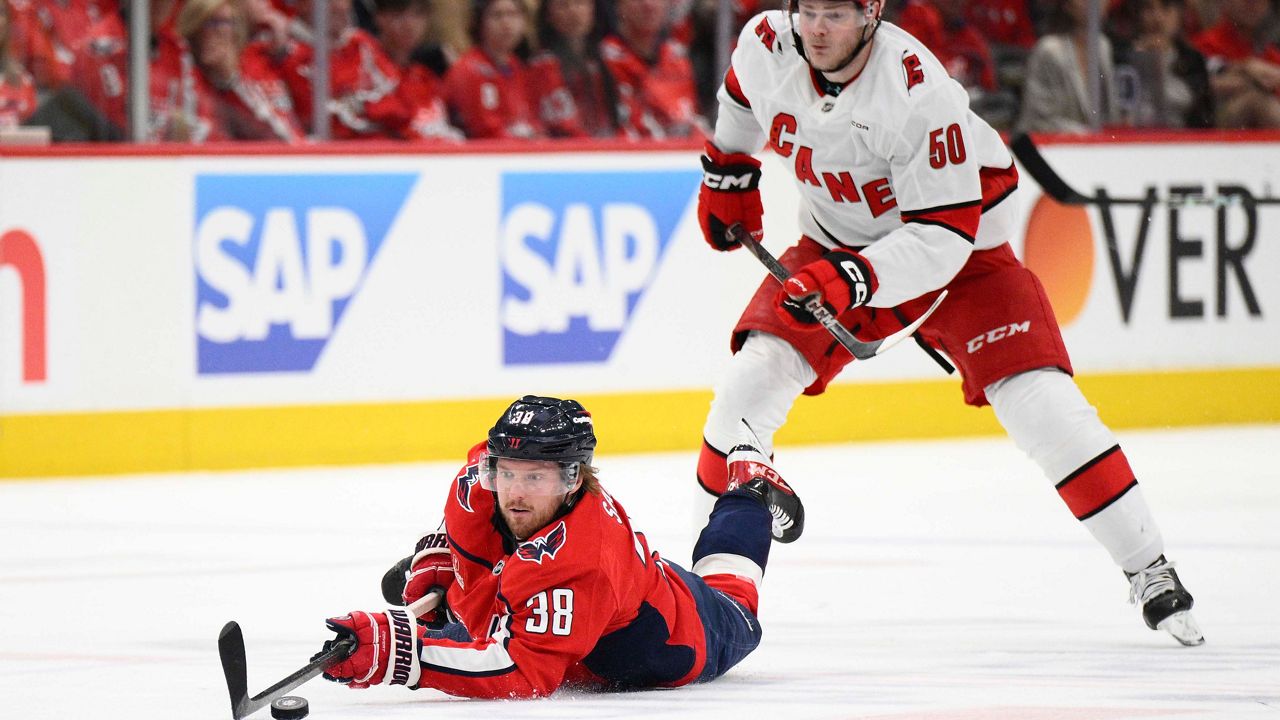 Washington Capitals defenseman Rasmus Sandin (38) dives for the puck past Carolina Hurricanes left wing Eric Robinson (50) in the second period of Game 2 of a second-round NHL hockey playoff series Thursday, May 8, 2025, in Washington. (AP Photo/Nick Wass)