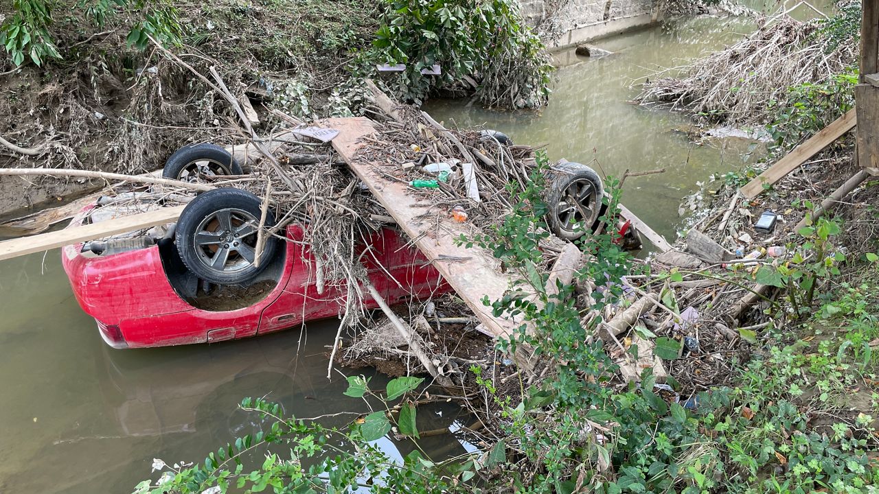 A red sedan upside down in the Troublesome Creek carried downstream by flood waters (Spectrum News 1/Mason Brighton)