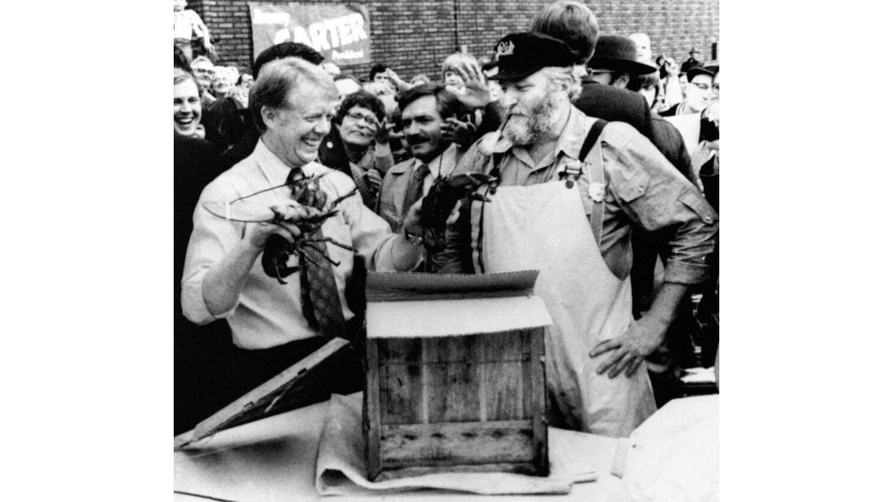 Then-Democratic presidential candidate Jimmy Carter, left, received two Maine lobsters from Captain Bruce Robertson-Dick, right, harbormaster of Ogunquit, in Biddeford, Maine, Oct. 1, 1976. The presentation was made outside St. Joseph's Church where Carter had just addressed a rally.  The Democratic nominee took the lobsters with him as his campaign left the state. (AP Photo)