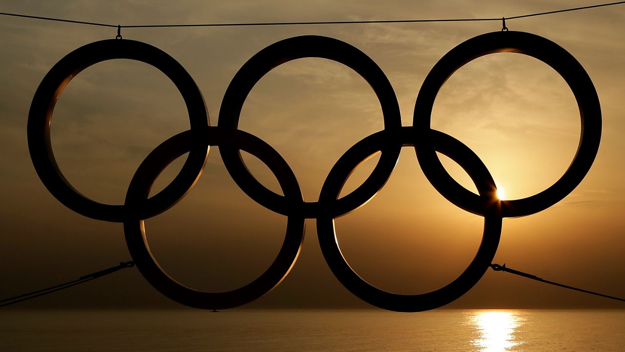 In this Monday, Feb. 24, 2014 file photo, People stand under a set of Olympic Rings as they watch the sun set over the Black Sea a day after the close of the 2014 Winter Olympics, in Sochi, Russia. (AP Photo/Charlie Riedel, File)