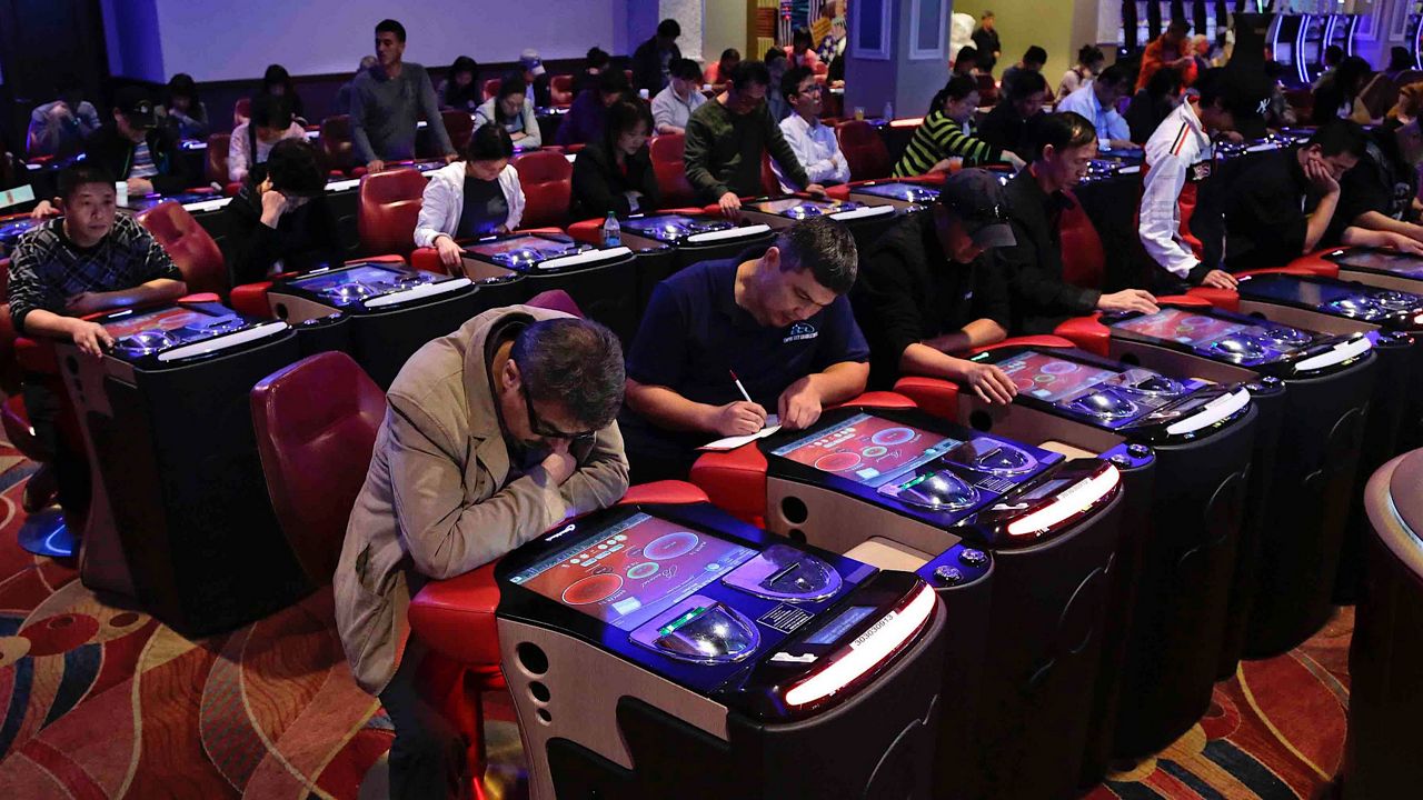 In this Oct. 3, 2014, file photo, visitors to the Resorts World Casino at the Aqueduct racetrack play electronic baccarat games, in the Queens borough of New York. (AP Photo/Julie Jacobson, File)