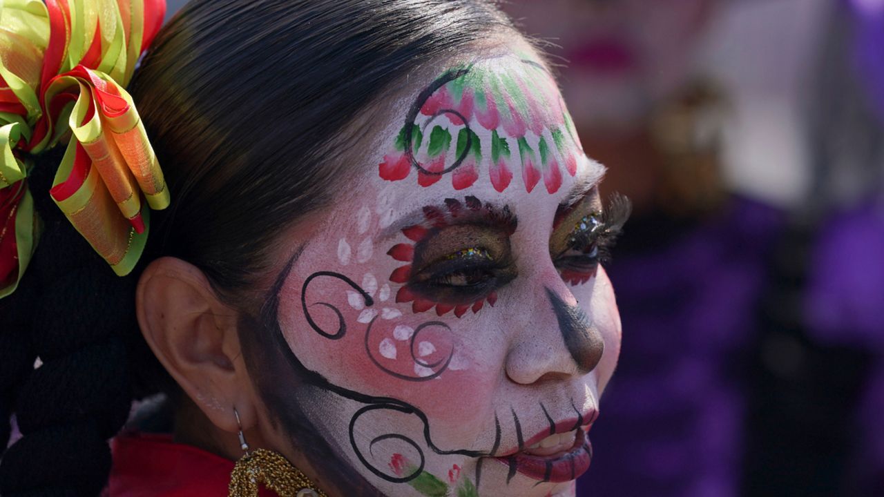 A woman dressed as a "Catrina" poses for a photo during Day of the Dead festivities in Mexico City, Sunday, Oct. 31, 2021. Altars and artwork from around the country were on display in a parade, as Mexicans honor Day of the Dead. (AP Photo/Fernando Llano)