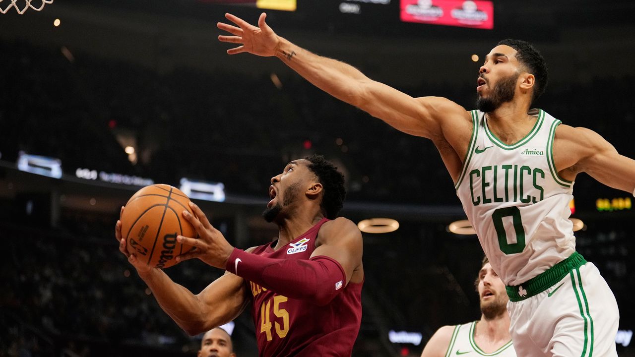 Cleveland Cavaliers guard Donovan Mitchell (45) goes to the basket in front of Boston Celtics forward Jayson Tatum (0) in the first half of an NBA basketball game, Sunday, Dec. 1, 2024, in Cleveland. (AP Photo/Sue Ogrocki)