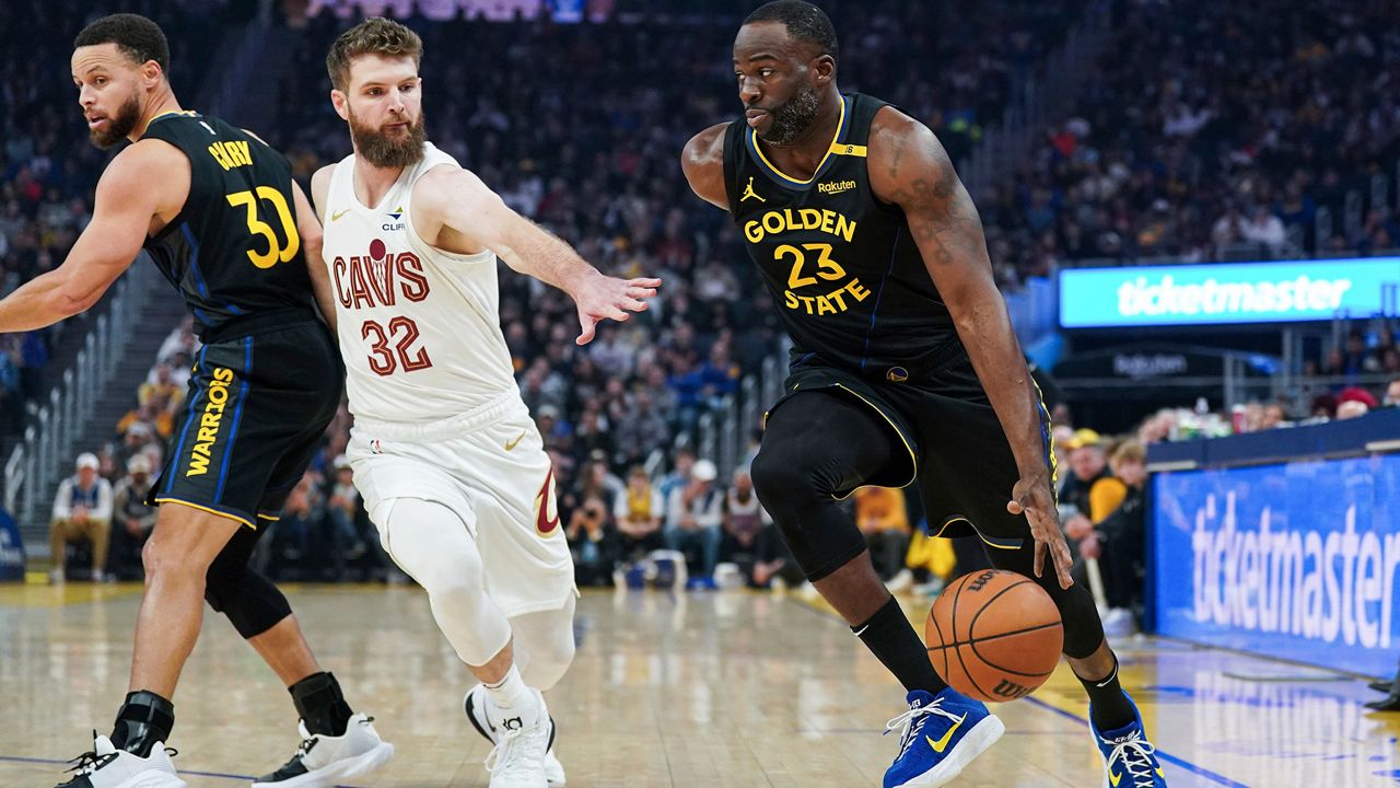 Golden State Warriors forward Draymond Green, right, moves the ball while defended by Cleveland Cavaliers guard Dean Wade (32) during the first half of an NBA basketball game Monday, Dec. 30, 2024, in San Francisco. (AP Photo/Kavin Mistry)