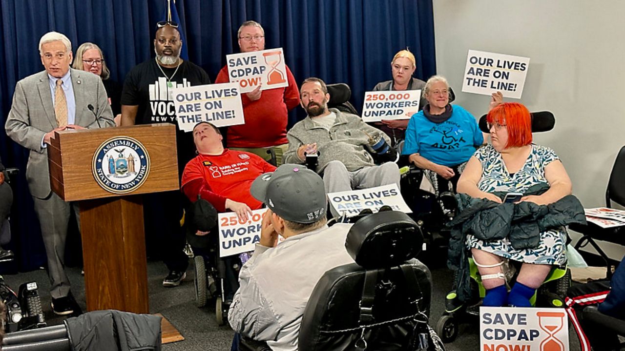 Assemblyman David Weprin speaks in the Legislative Office Building, surrounded by ralliers, some in wheelchairs