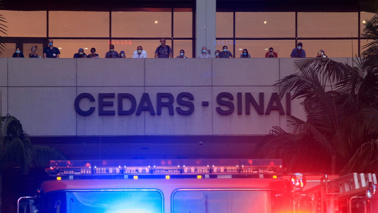 In this May 6, 2020, file photo, hospital personnel take photos from a balcony at Cedars-Sinai Medical Center in Los Angeles. (AP Photo/Damian Dovarganes)