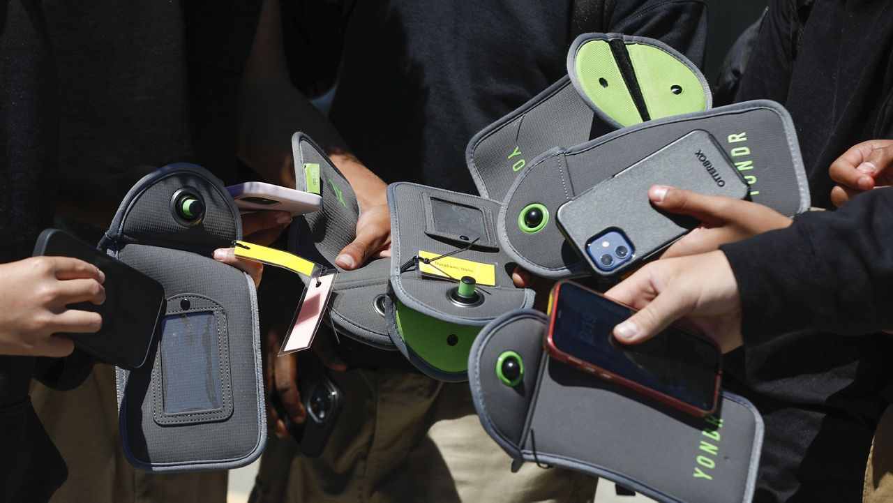 A student uses a cell phone after unlocking the pouch that secures it from use during the school day at Bayside Academy, Aug. 16, 2024, in San Mateo, Calif. (Lea Suzuki/San Francisco Chronicle via AP, File)