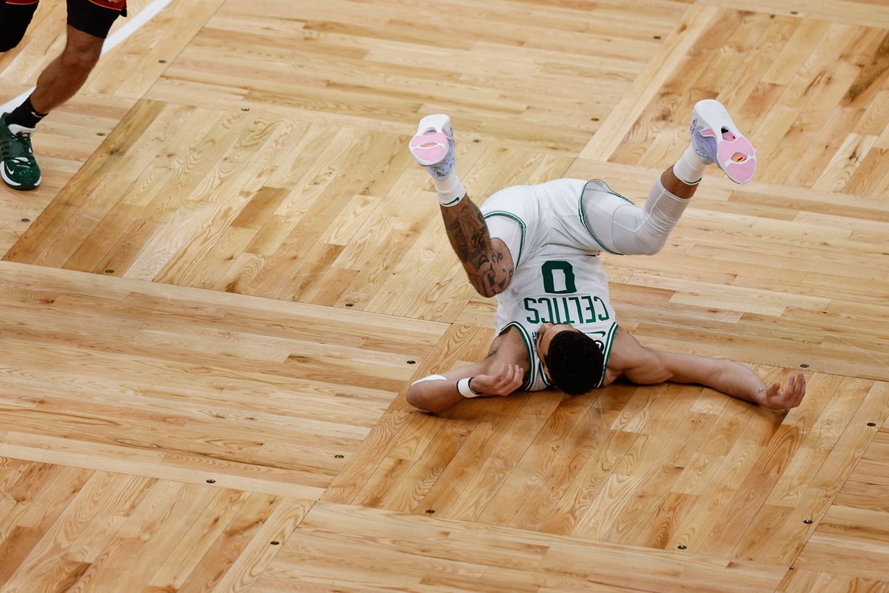 Boston Celtics forward Jayson Tatum (0) falls to the court in the first half of Game 1 of the NBA basketball Eastern Conference finals playoff series against the Miami Heat in Boston, Wednesday, May 17. (AP Photo/Michael Dwyer)