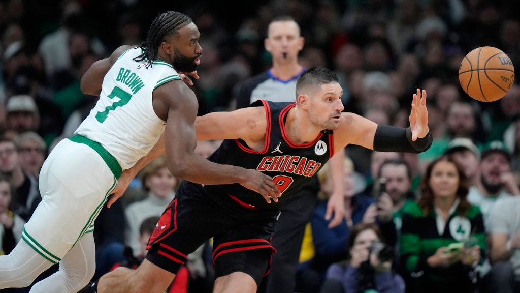 Boston Celtics guard Jaylen Brown (7) and Chicago Bulls center Nikola Vucevic (9) chase a loose ball in the second half of an NBA basketball game, Thursday, Dec. 19, 2024, in Boston. (AP Photo/Steven Senne)