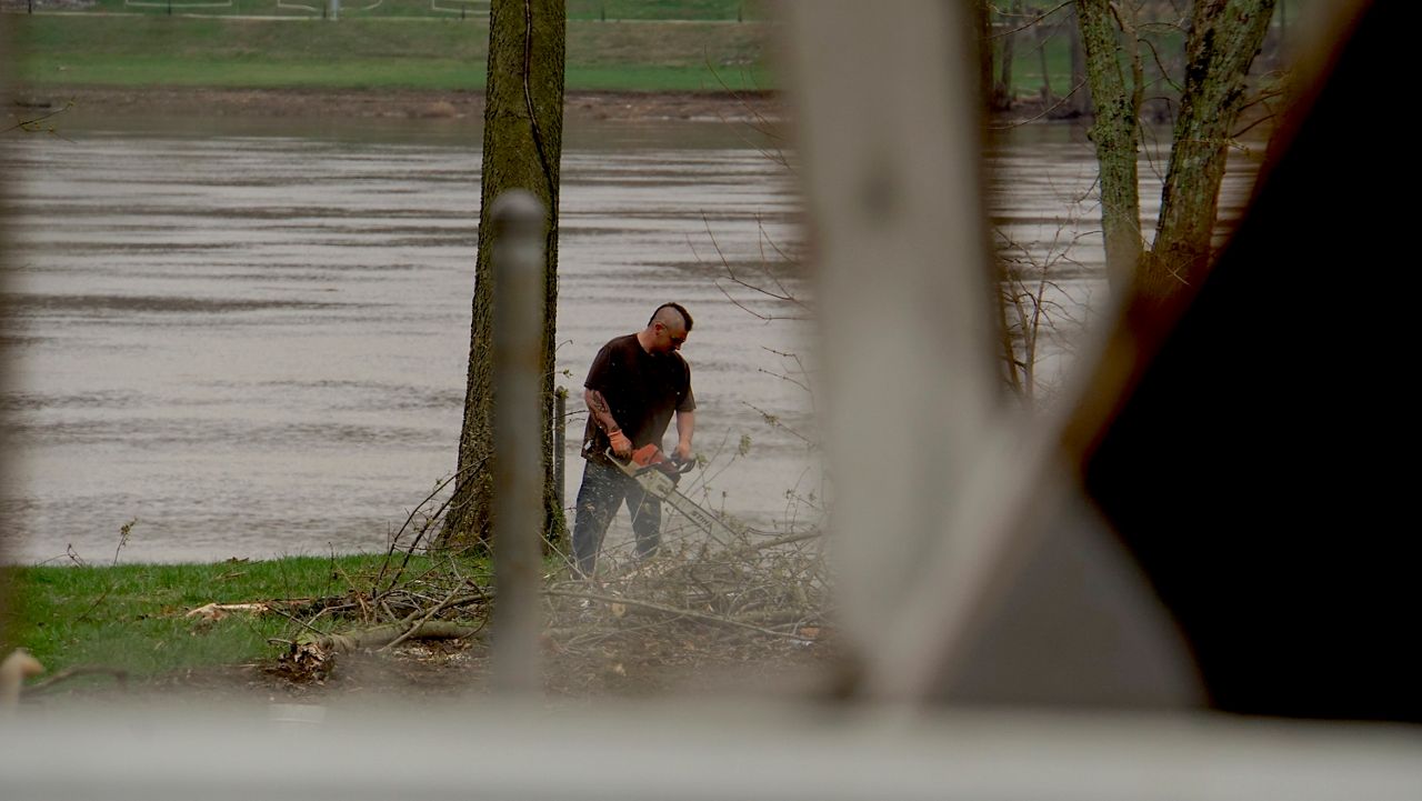 Clinton Smith uses a chainsaw to cut up fallen tree branches after the March 14 tornado (Spectrum News 1/Mason Brighton)