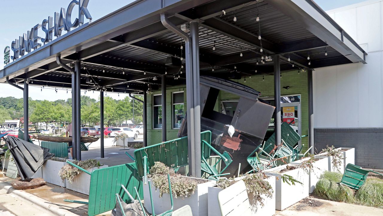 Chairs, umbrellas and a large garbage container are among the debris washed up at the Shake Shack in the Eastgate Shopping Center after it flooded during Tropical Storm Chantal, Monday, July 7, 2025, in Chapel Hill, N.C. (AP Photo/Chris Seward)