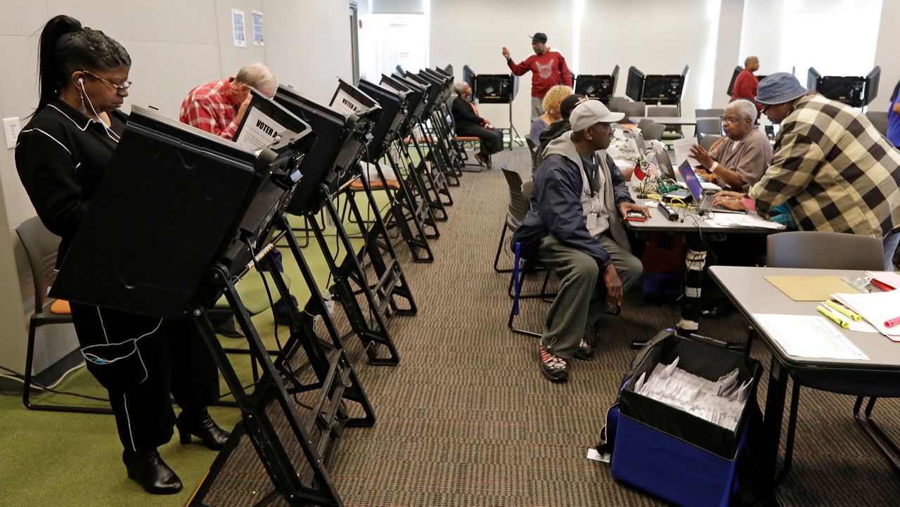 Voters register and cast ballots during early voting at a polling place in Charlotte, N.C., Tuesday, Oct. 23, 2018. (AP File Photo/Chuck Burton)