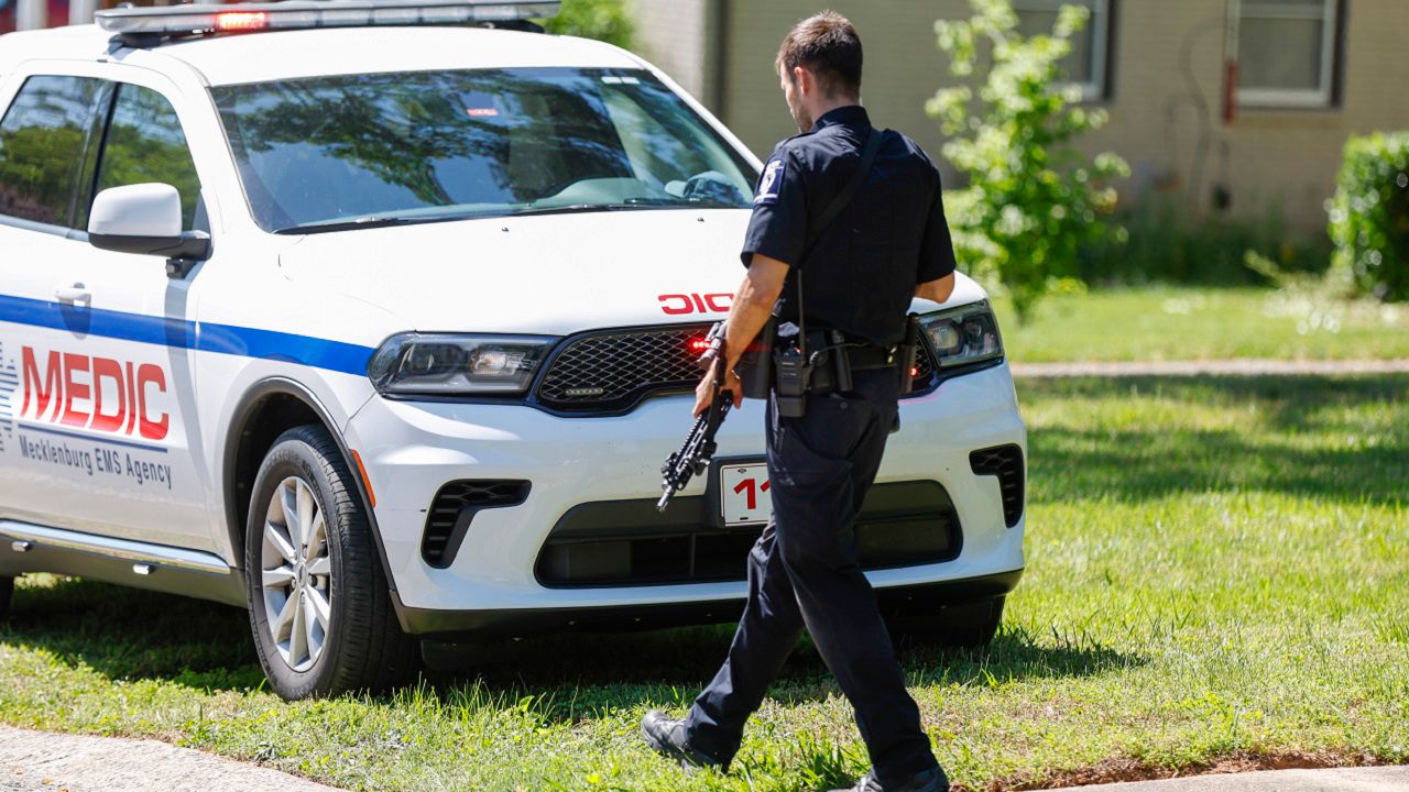 A Charlotte Mecklenburg Police Department officer walks carrying a gun in the neighborhood where a shooting took place in Charlotte, N.C., Monday, April 29, 2024. CMPD says officers from the U.S. Marshals Task Force were carrying out an investigation Monday afternoon in a suburban neighborhood when they came under gunfire. (AP Photo/Nell Redmond)