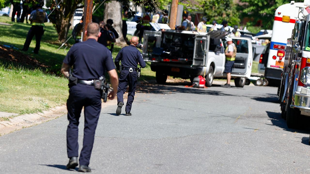 Charlotte-Mecklenburg Police Department officers walk in the neighborhood where a deadly shootout took place as a U.S. Marshals Service task force tried to arrest a suspect in Charlotte, N.C., Monday, April 29, 2024. (AP Photo/Nell Redmond)
