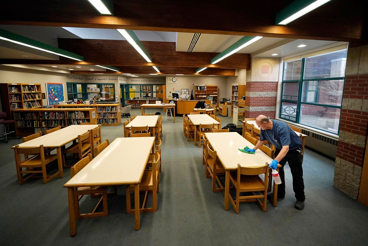 Custodian David Bishop cleans pencil marks from desks in the Hampden Academy library, Tuesday, April 25, in Hampden. In addition to his custodial duties, Bishop also serves as the chess coach for district's nationally recognized middle school chess team. (AP Photo/Robert F. Bukaty)