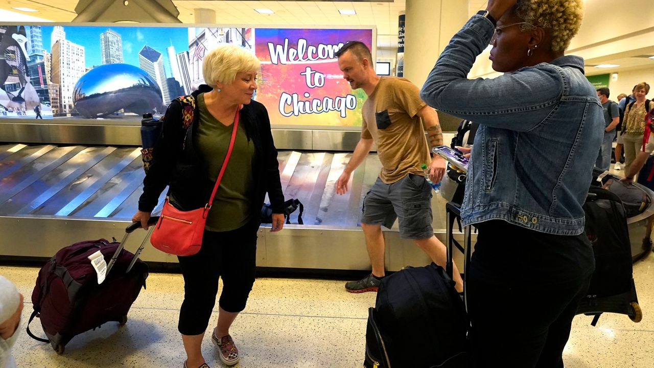 Airline passengers retrieve luggage at Chicago's Midway International Airport on the first day of the Fourth of July holiday weekend Friday, July 1, 2022, in Chicago. (AP Photo/Charles Rex Arbogast)