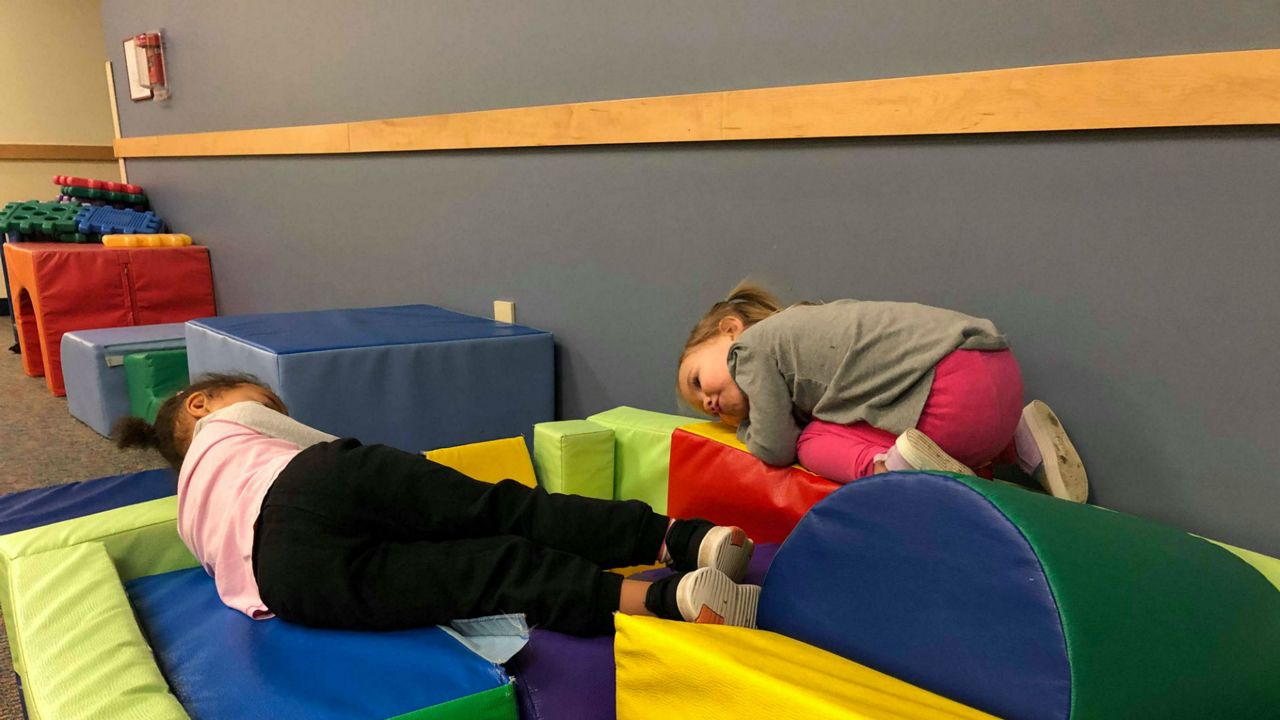 Two small children lay on a play area (Spectrum News/File)