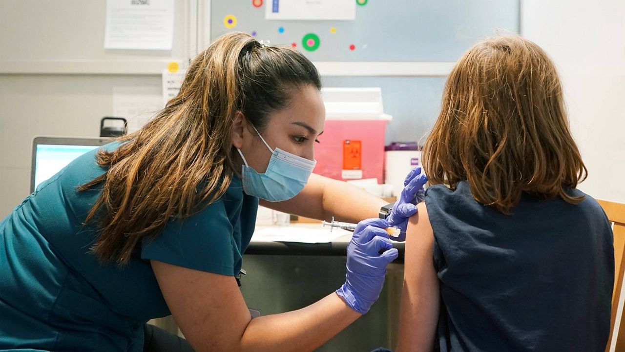 Courtney Martin, left, a nurse at the University of Washington Medical Center, gives the first shot of the Pfizer COVID-19 vaccine to Ani Hahn, 7, on Tuesday in Seattle. (AP Photo/Ted S. Warren)