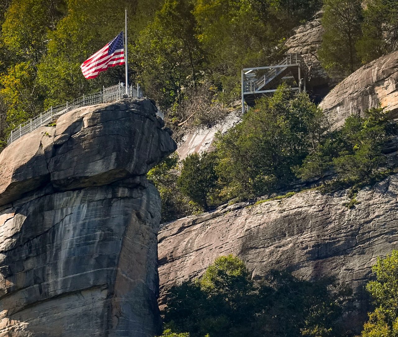 An American flag flies half-staff on top of Chimney Rock mountain in the aftermath of Hurricane Helene, Wednesday, Oct. 2, 2024, in Chimney Rock Village, N.C. (AP Photo/Mike Stewart)