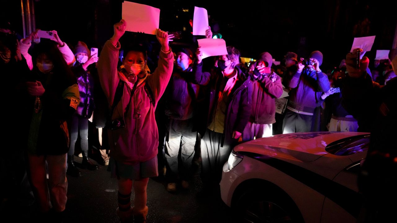 Protesters hold up blank papers and chant slogans as they march in protest in Beijing on Sunday. (AP Photo/Ng Han Guan)