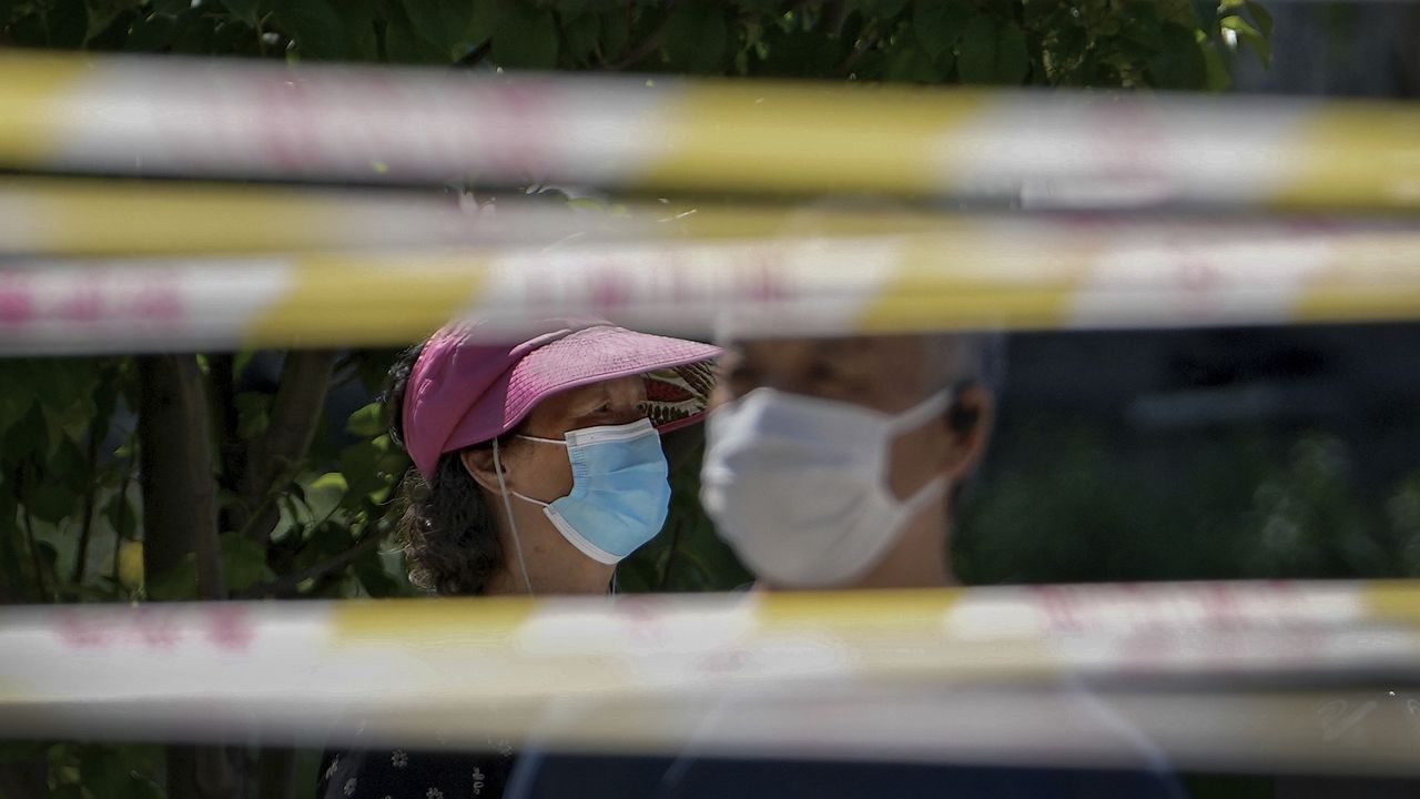 Residents wearing face masks line up behind barricaded tapes for COVID mass testing near a residential area on May 15, 2022, in Beijing. (AP Photo/Andy Wong, File)