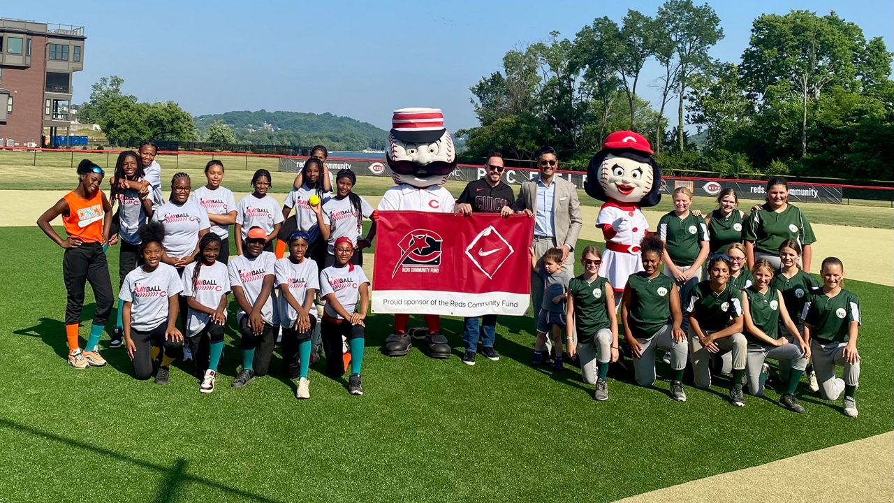 Mayor Aftab Pureval and former Reds pitcher Sam LeCure pose with players on two Cincinnati-area softball teams. They were there for the rededication and beautification of PNC Field in Cincinnati’s East End. (Spectrum News 1/Casey Weldon)