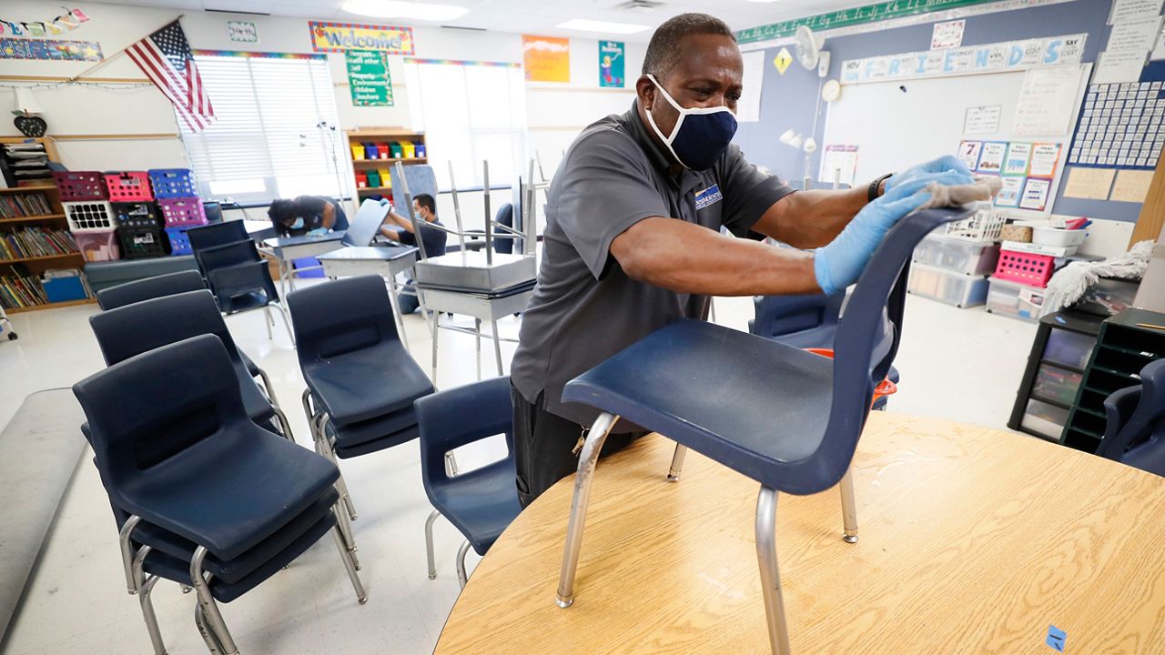 A janitor sanitizes a classroom to prevent COVID-19 from spreading. 