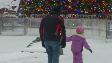 parent holding child's hand as they skate on ice