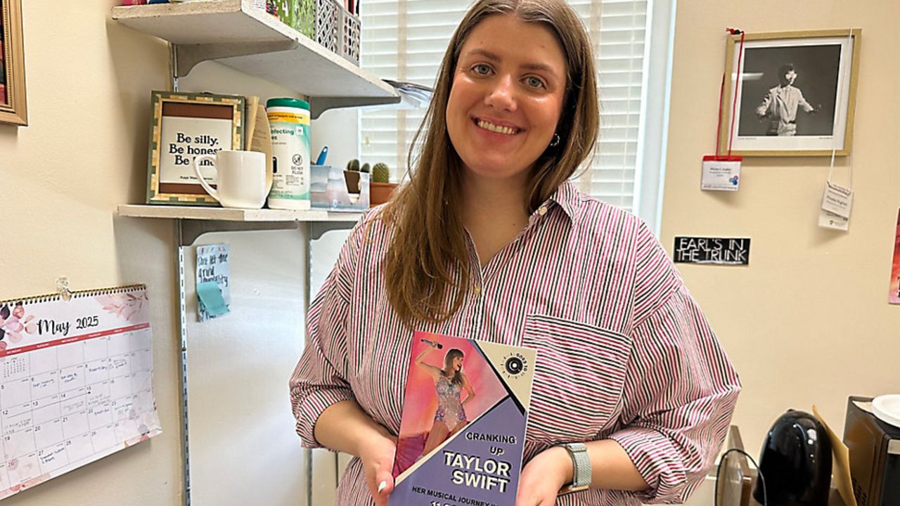 woman holds book she wrote on taylor swift