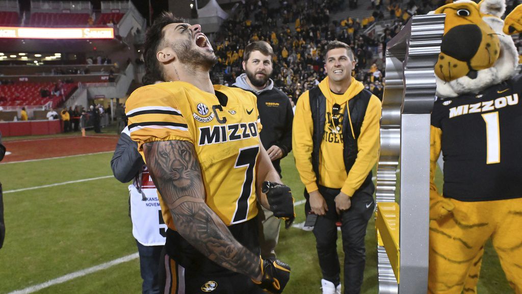 Missouri running back Cody Schrader (7) celebrates next to the Battle Line trophy after the team's win over Arkansas in an NCAA college football game Friday, Nov. 24, 2023, in Fayetteville, Ark. (AP Photo/Michael Woods)
