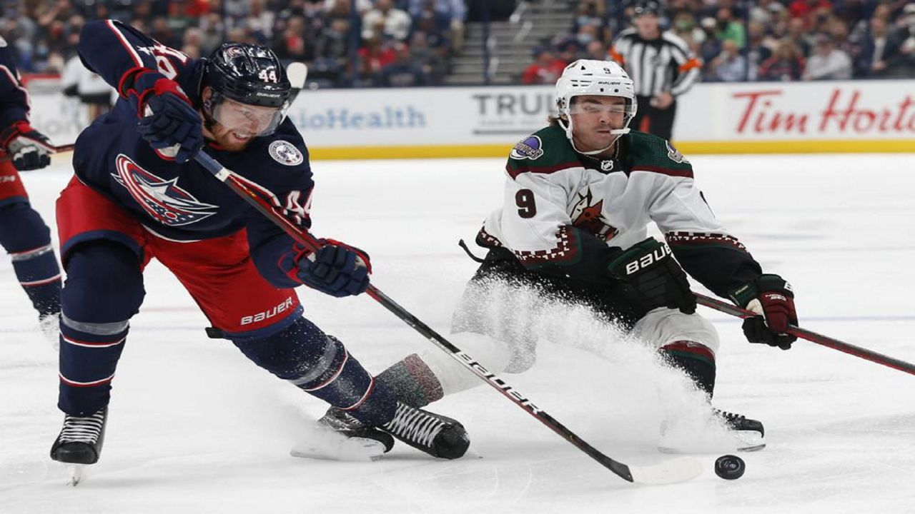 Columbus Blue Jackets' Vladislav Gavrikov, left, tries to clear the puck past Arizona Coyotes' Clayton Keller during the first period of an NHL hockey game Thursday, Oct. 14, 2021, in Columbus, Ohio. (AP Photo/Jay LaPrete)