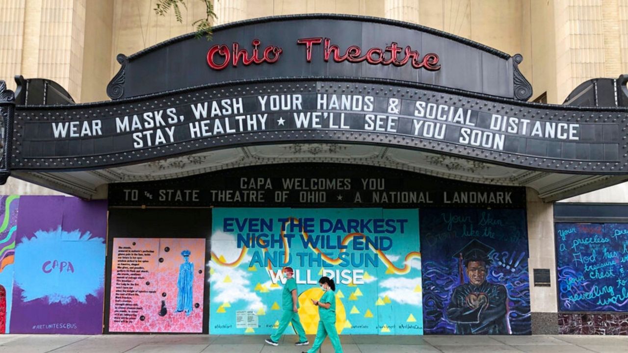 FILE — In this Aug. 26, 2020 file photo, workers in scrubs and masks walk by the Ohio Theatre in Columbus, Ohio, amid the coronavirus pandemic. (AP Photo/Julie Carr Smyth, File)