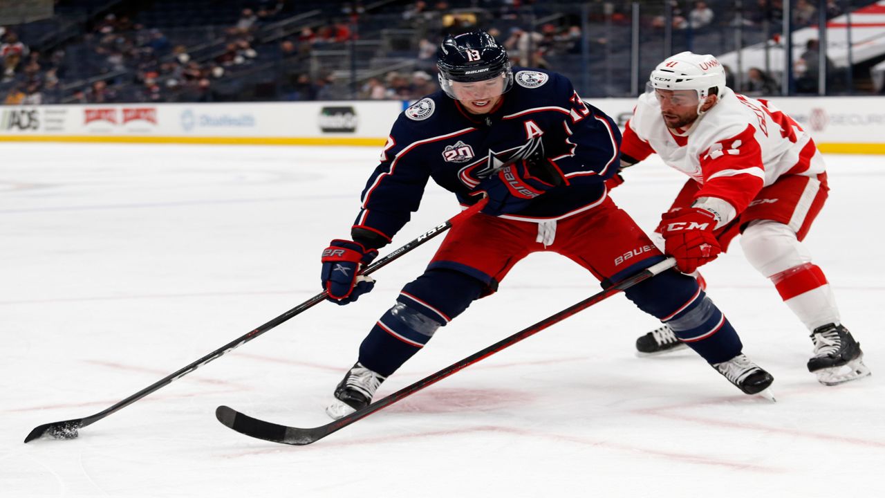 Columbus Blue Jackets forward Cam Atkinson, left, controls the puck in front of Detroit Red Wings forward Luke Glendening during the second period of an NHL hockey game in Columbus, Ohio, Saturday, May 8, 2021. (AP Photo/Paul Vernon)