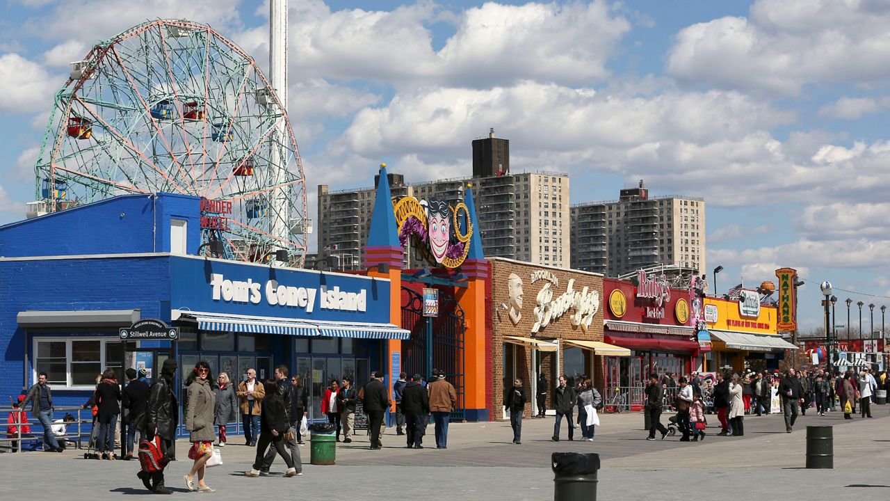 Visitors to New York's Coney Island walk on the boardwalk.
