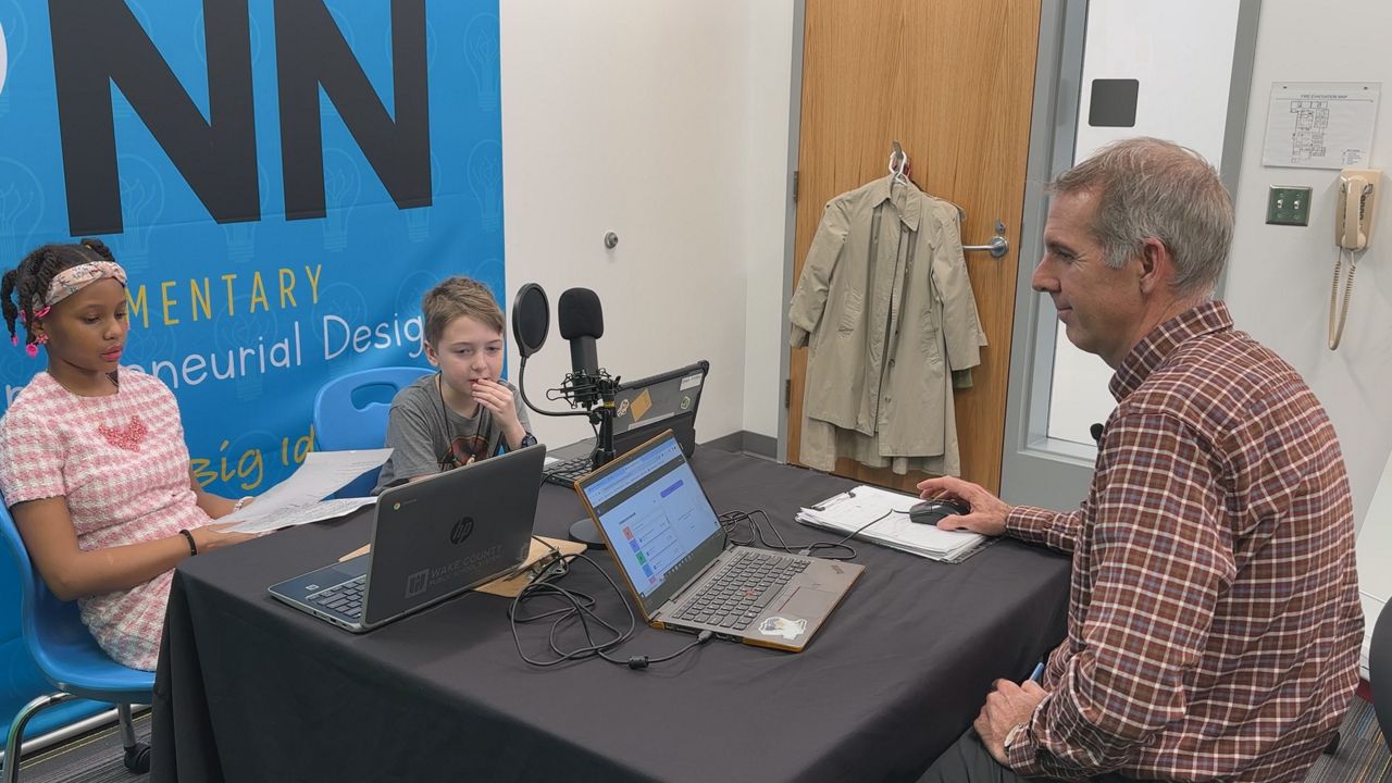 Dan Gridley helps students record a school podcast. (Spectrum News 1/Rob Wu)