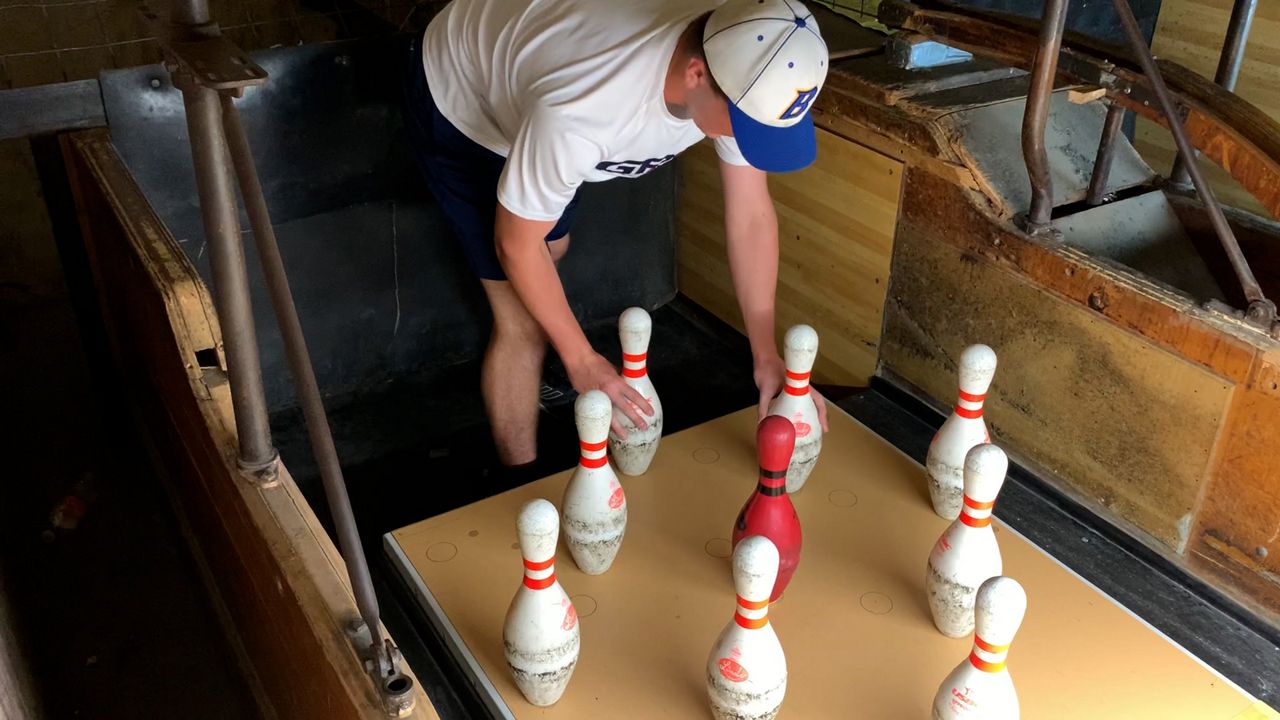 Eschewing modernity, Conner Chase picks up pins at a bowling alley in this image from May 2021. (Spectrum News 1/Adam Rossow)