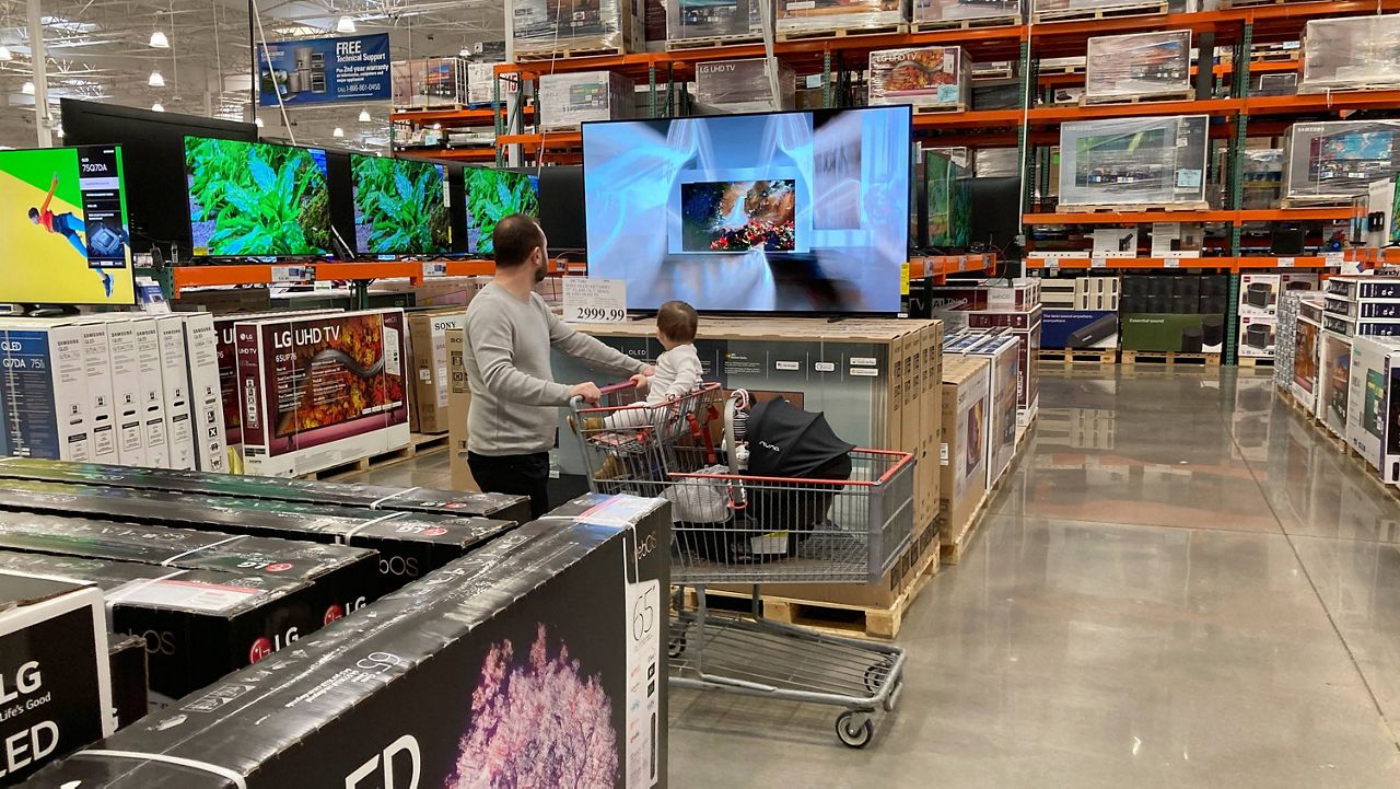 A shopper pushes a child in a cart while browsing big-screen televisions on display in the electronics section of a Costco warehouse in Lone Tree, Colo. (AP Photo/David Zalubowski, File)