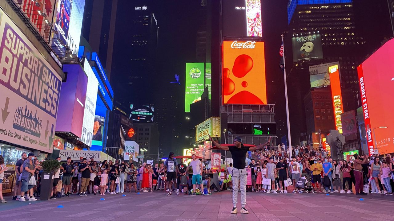 A crowd of spectators gather around a dancer in Times Square.