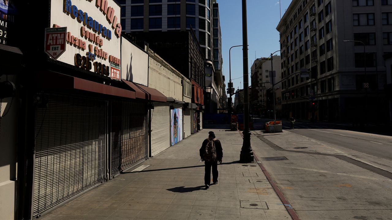 A man walks on a sidewalk lined with shuttered shops Wednesday, June 3, 2020, in downtown Los Angeles, as protests continue over the death of George Floyd on May 25 in Minneapolis. Los Angeles County pushed back the start of its curfew from 6 p.m. to 9 p.m., a help to newly reopened restaurants and retail stores that were shut down for weeks by anti-coronavirus orders. (AP Photo/Jae C. Hong)