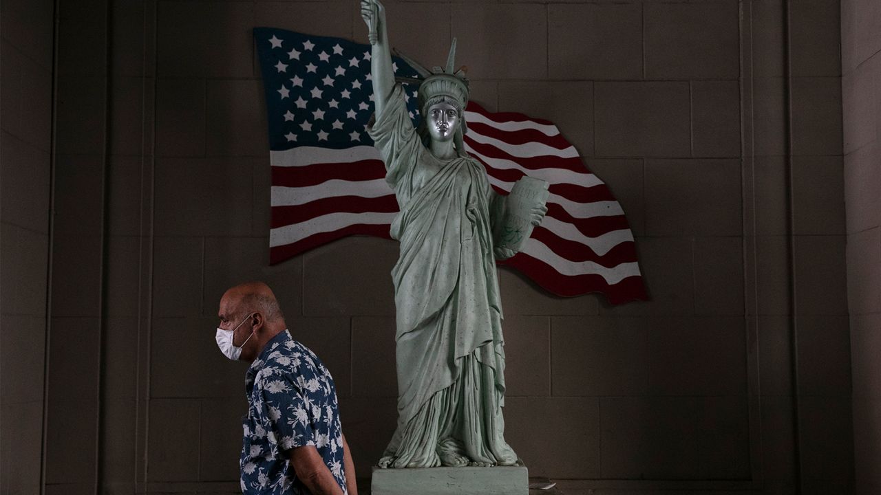A man with a face mask walks past a replica of Statue of Liberty, Monday, June 22, 2020, in Los Angeles. Alarming surges in coronavirus cases across the South and West raised fears Monday that the outbreak is spiraling out of control and that hard-won progress against the scourge is slipping away because of resistance among many Americans to wearing masks and keeping their distance from others. (AP Photo/Jae C. Hong)