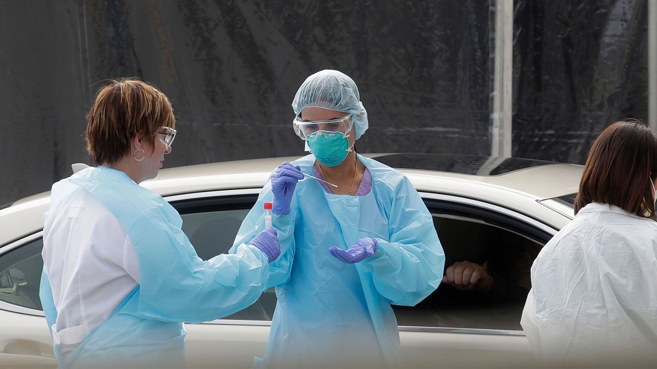 In this file photo, health care workers collect swabs from people who are suspected of having COVID-19. (Associated Press)