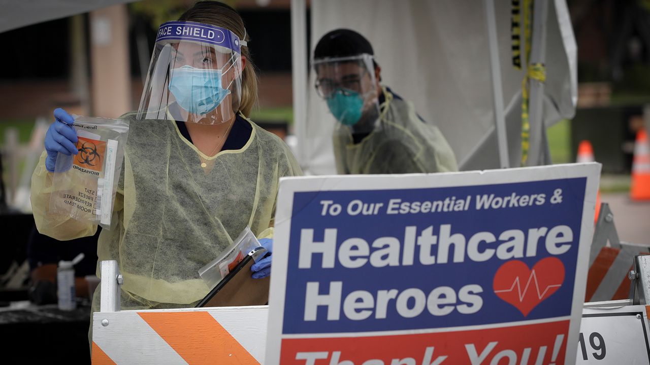 A worker hands out testing kits at a mobile Coronavirus testing site at the Charles Drew University of Medicine and Science Wednesday, July 22, 2020, in Los Angeles. California's confirmed coronavirus cases have topped 409,000, surpassing New York for most in the nation. (AP Photo/Marcio Jose Sanchez)