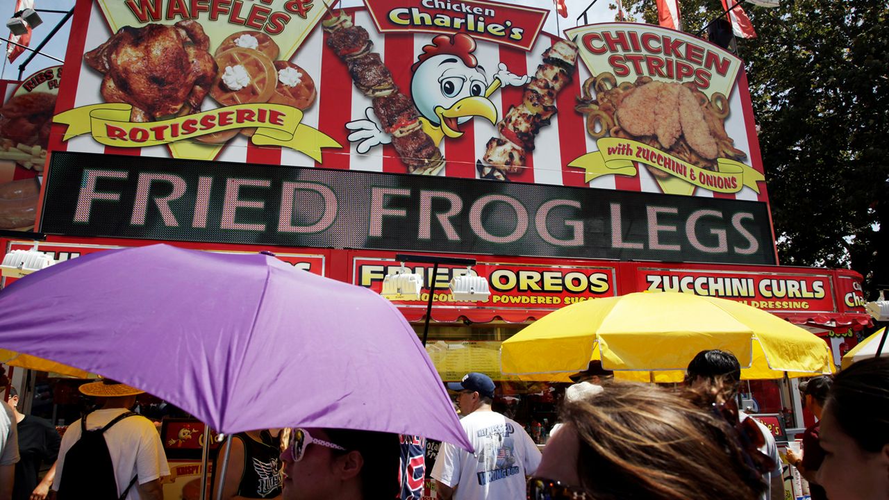 Fairgoers pass a food stand selling fried frog legs one of the many food stalls at the LA County Fair on Labor Day in Pomona Calif. on Monday Sept. 2, 2013. (AP Photo/Richard Vogel)