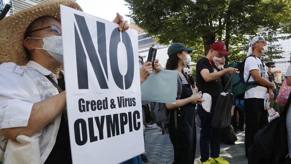 People gather for a rally in Tokyo's Shinjuku shopping district Sunday, July 18, 2021, to protest against the Olympics starting from July 23. They held signs that said No Olympics.(AP Photo/Yuri Kageyama)
