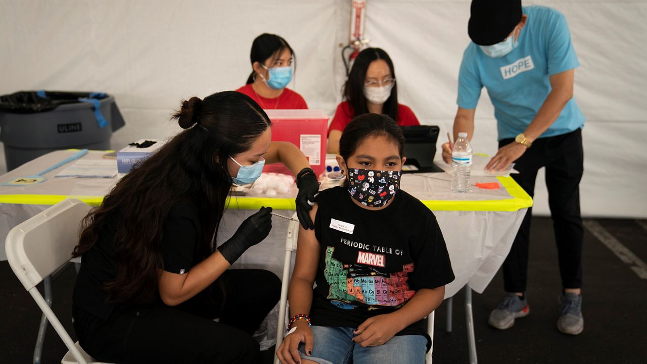 In this Aug. 28, 2021, file photo, Mayra Navarrete, 13, receives the Pfizer COVID-19 vaccine from registered nurse, Noleen Nobleza at a clinic set up in the parking lot of CalOptima in Orange, Calif. (AP Photo/Jae C. Hong)