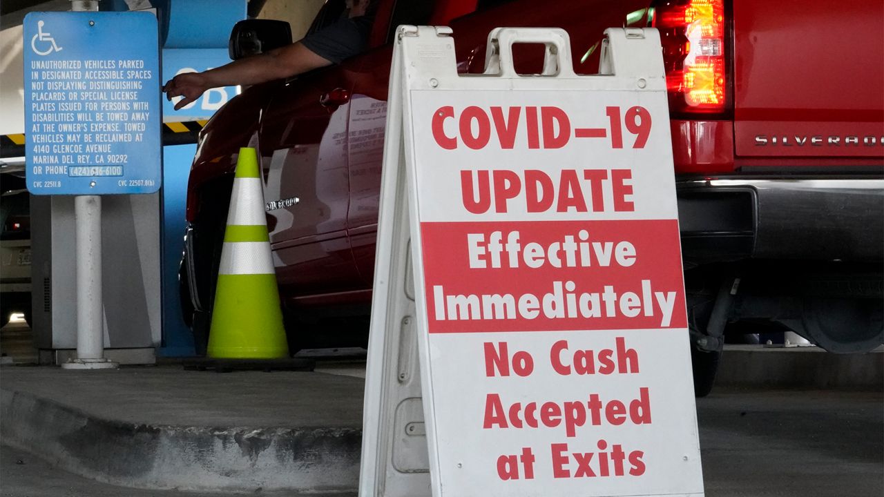 A sign posted reads "Covid-19 Update. Effective Inmediately. No Cash Accepted at Exits," at a Los Angeles International Airport main parking lot in Los Angeles, Friday, Nov. 13, 2020.(AP Photo/Damian Dovarganes)