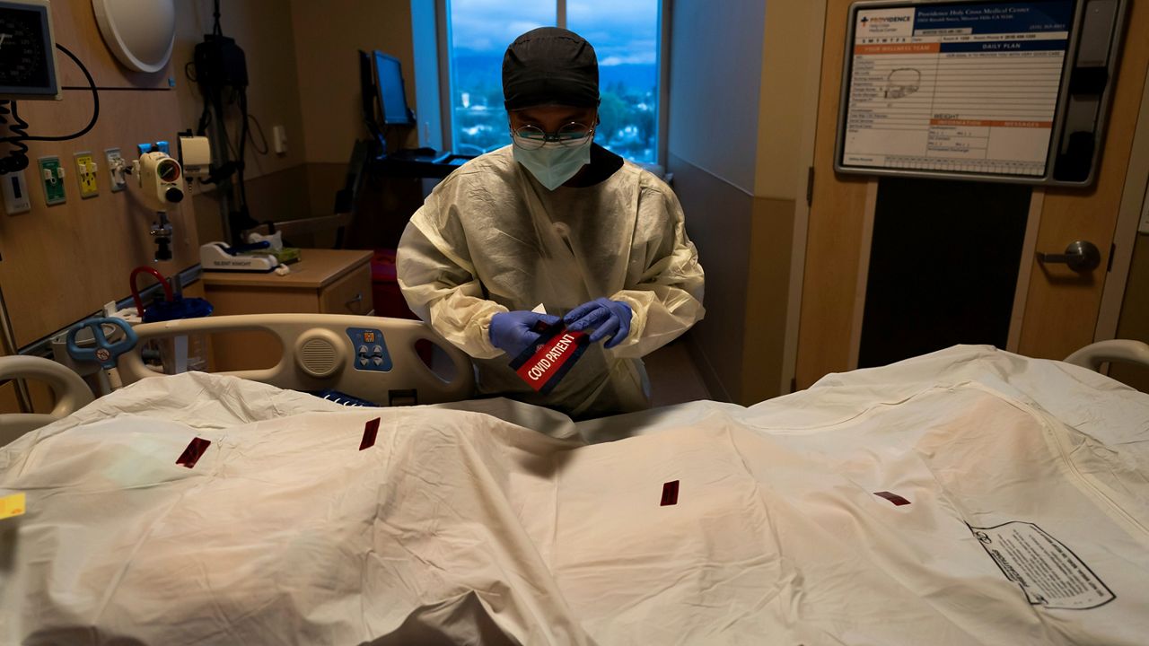 Registered nurse Bryan Hofilena attaches a "COVID Patient" sticker on a body bag of a patient who died of coronavirus at Providence Holy Cross Medical Center in Los Angeles, on Dec. 14, 2021. (AP Photo/Jae C. Hong, File )